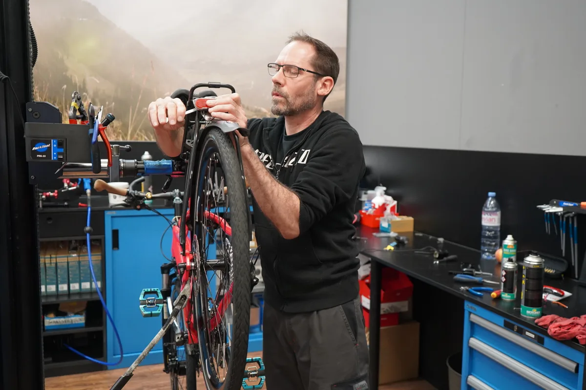 Man sieht Marcel beim Reparieren eines Velos.